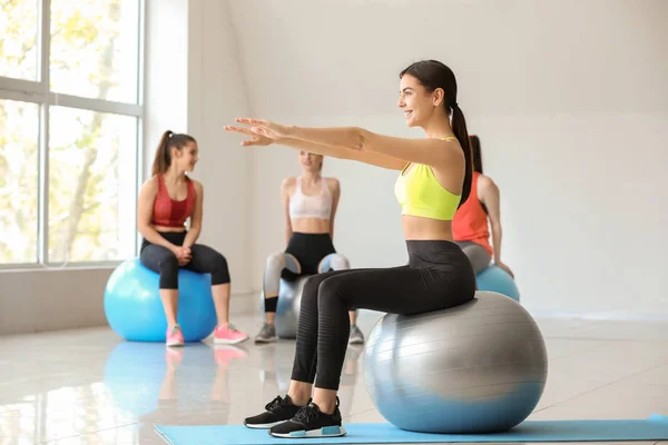 Jovem mulher esportiva fazendo exercícios com fitball no ginásio — Fotografia de Stock