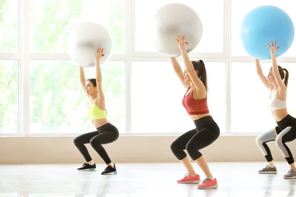 Jóvenes deportistas haciendo ejercicios con fitballs en el gimnasio —  Fotos de Stock