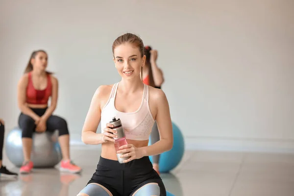 Young sporty woman with fitball drinking water in gym — Stock Photo, Image
