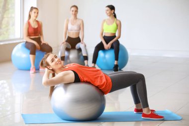 Spor salonunda fitball ile egzersiz yapan genç sportif kadın
