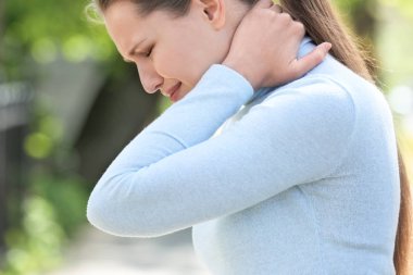 Genç kadın açık havada boyun ağrısı muzdarip