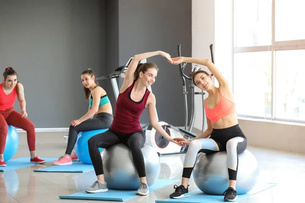 Jóvenes deportistas haciendo ejercicios con fitballs en el gimnasio —  Fotos de Stock