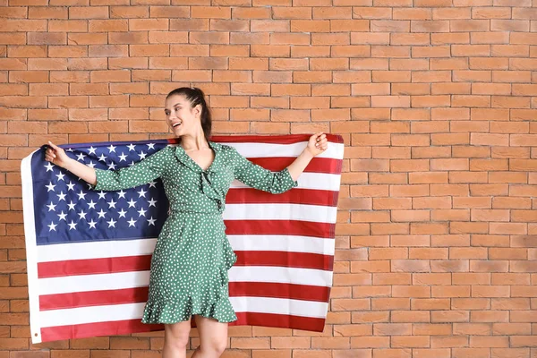 Happy young woman with national flag of USA on brick background — Stock Photo, Image