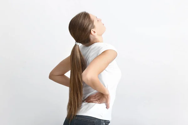 Junge Frau leidet unter Rückenschmerzen auf weißem Hintergrund — Stockfoto
