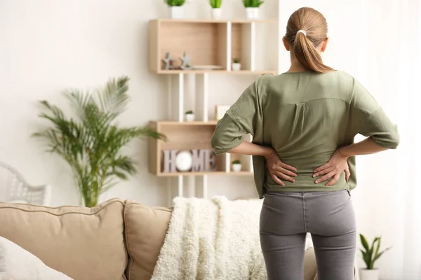 Young woman suffering from back pain at home — Stock Photo, Image