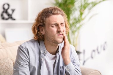 Genç adam evinde diş ağrısı çekiyor.