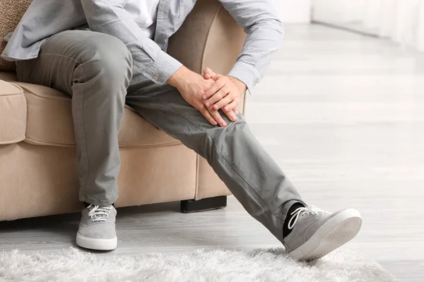 Jeune homme souffrant de douleur à la jambe à la maison — Photo