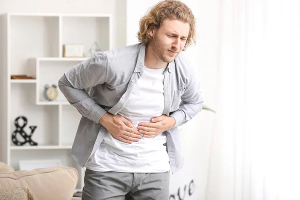 Mladý muž trpící bolesti břicha doma — Stock fotografie