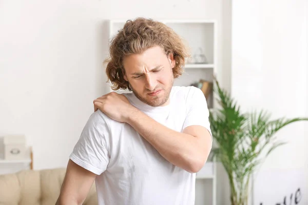 Young man suffering from pain in shoulder at home — Stock Photo, Image