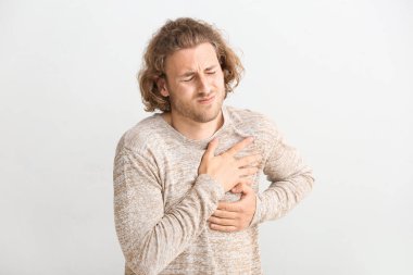 Genç adam beyaz arka plan üzerinde göğüs ağrısı muzdarip