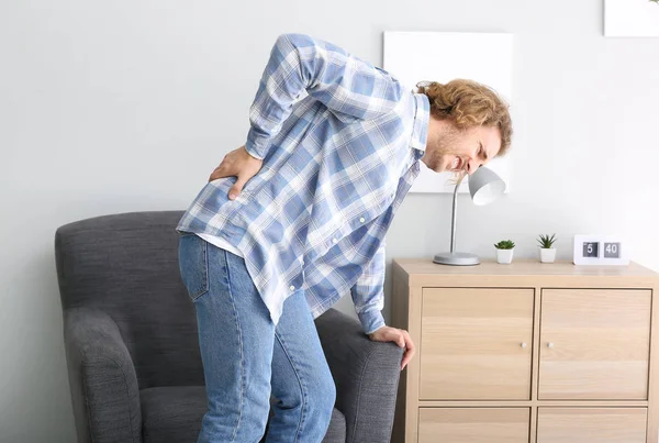 Jovem sofrendo de dor nas costas em casa — Fotografia de Stock