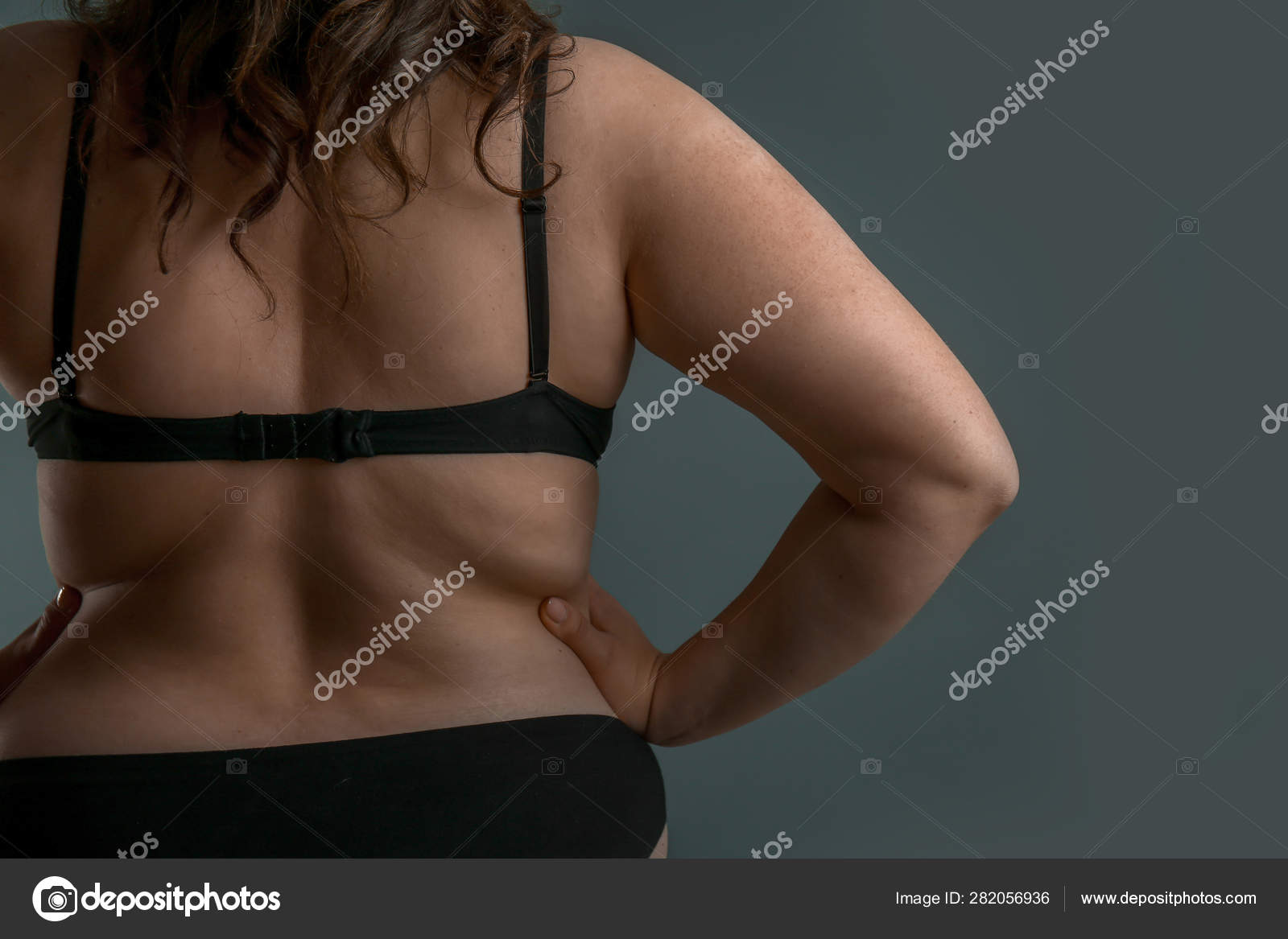 Beautiful plus size woman on grey background, back Concept