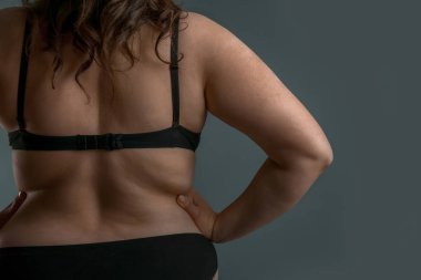 Gri arka planda güzel artı beden kadın, arka görünüm. Vücut pozitif kavramı