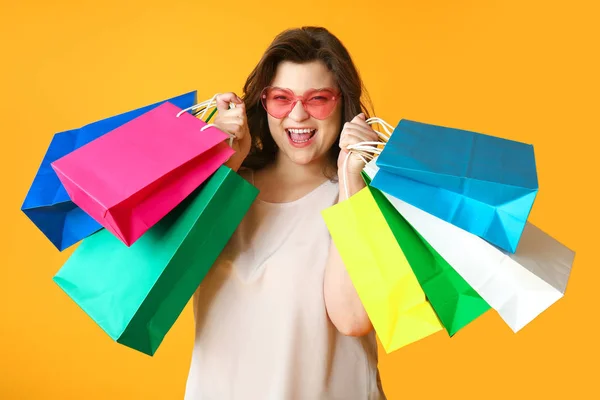 Glücklich plus size Frau mit Einkaufstaschen auf farbigem Hintergrund — Stockfoto