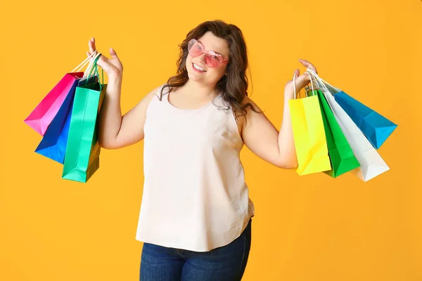 Happy plus size woman with shopping bags on color background — Stock Photo, Image