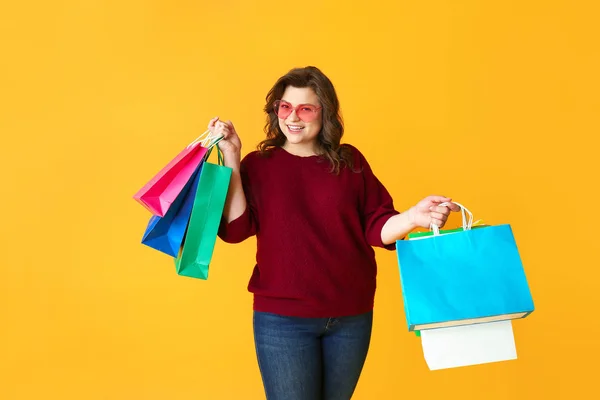 Mujer feliz más tamaño con bolsas de compras en el fondo de color —  Fotos de Stock