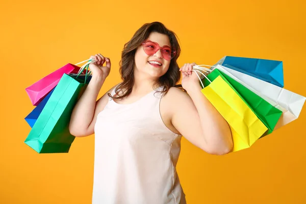 Щаслива жінка плюс розмір з сумками на кольоровому фоні — стокове фото
