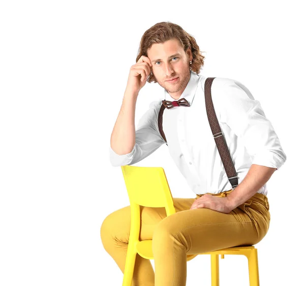 Stylish young man sitting on chair against white background — Stock Photo, Image