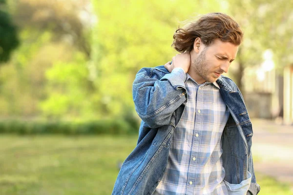 Young man suffering from neck pain outdoors — Stock Photo, Image