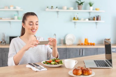 Güzel kadın evde mutfakta taze salata fotoğraf çekmek