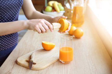 Güzel kadın evde mutfakta portakal suyu hazırlanıyor