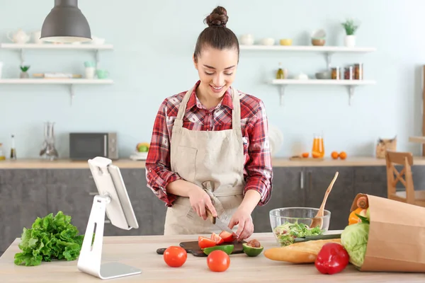 Beautiful woman preparing tasty vegetable salad in kitchen at home — Stock Photo, Image