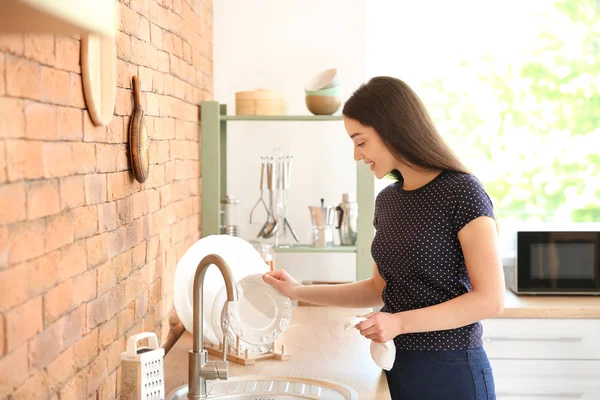 Mulher bonita limpando pratos na cozinha em casa — Fotografia de Stock
