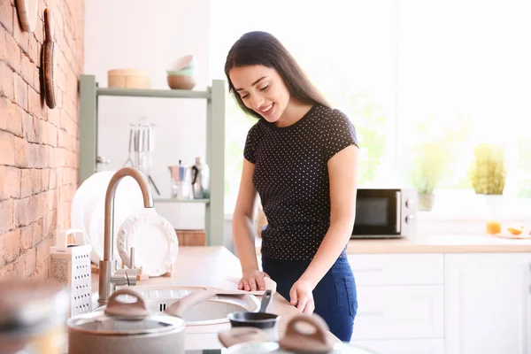 Beautiful woman cleaning table in kitchen at home — Stock Photo, Image
