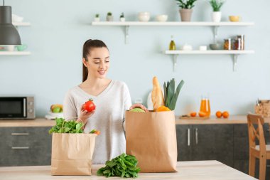 Evde mutfakta taze ürünlerle dolu alışveriş torbaları ile güzel kadın