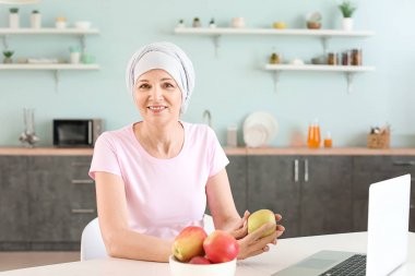 Mature woman after chemotherapy in kitchen at home clipart