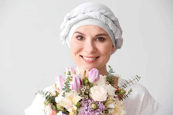 Mujer después de la quimioterapia con ramo de flores sobre fondo claro — Foto de Stock