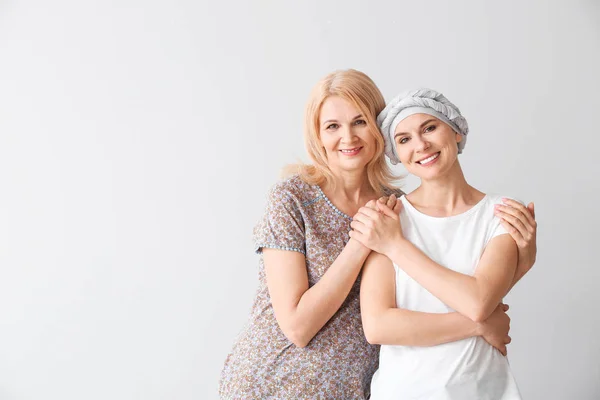 Woman after chemotherapy with her mother on light background — Stock Photo, Image