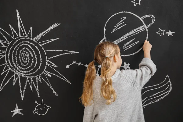 Little girl drawing space on dark wall