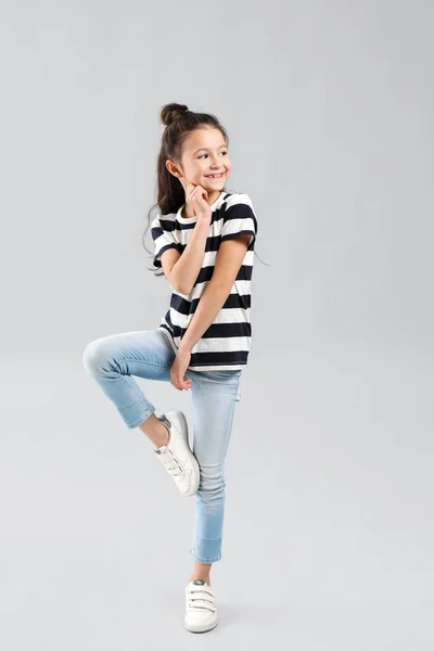 Happy girl in jeans on grey background — Stock Photo, Image