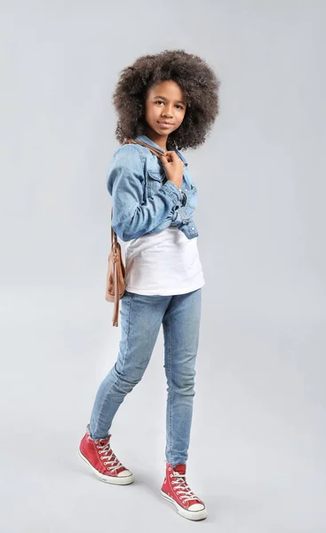 Stylish African-American girl in jeans clothes on grey background — Stock Photo, Image