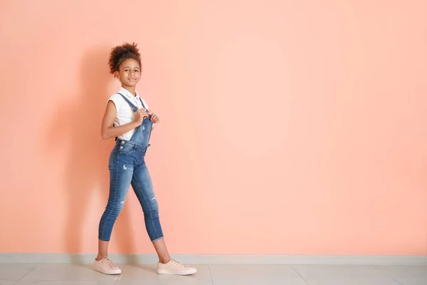 Elegante ragazza afro-americana in jeans generale vicino alla parete di colore — Foto Stock