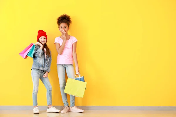 Chicas elegantes en jeans y con bolsas de compras cerca de la pared de color —  Fotos de Stock