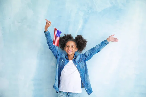 Carino ragazza afro-americana con bandiera nazionale degli Stati Uniti su sfondo di colore — Foto Stock