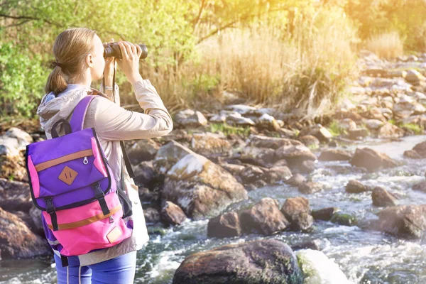 Female tourist near mountain stream on spring day