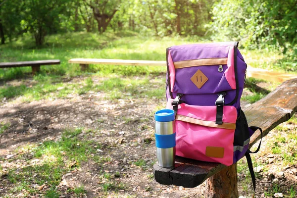 Туристичний рюкзак з термосом на лавці в лісі — стокове фото