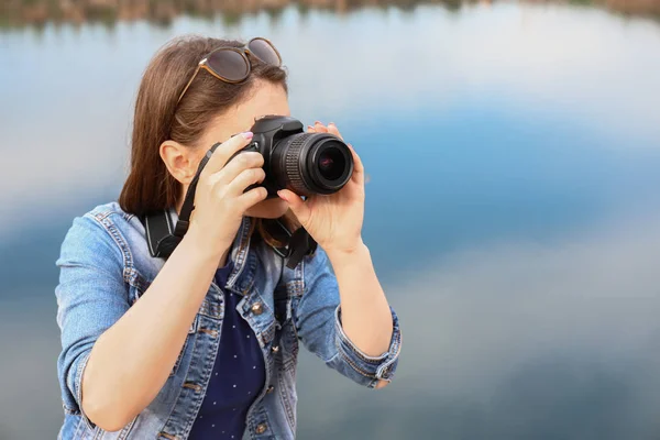 Turista femenina tomando fotos cerca del lago de montaña — Foto de Stock