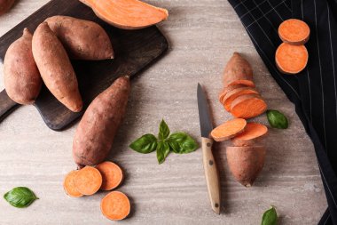 Gri arka planda çiğ tatlı patates ile kesme tahtası ve bıçak