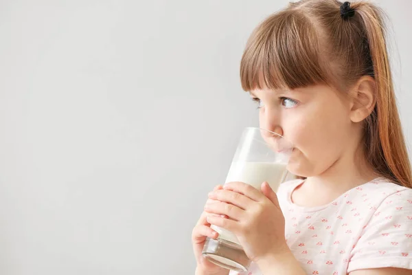 一杯牛奶在浅色背景上的可爱小女孩 — 图库照片