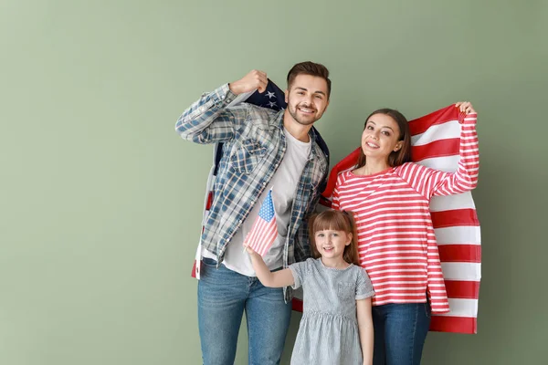 Happy young family with national flags of USA on color background — Stock Photo, Image