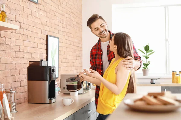 Young couple using coffee machine in kitchen — Stock Photo, Image