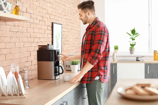 Handsome man using coffee machine in kitchen — Stock Photo, Image