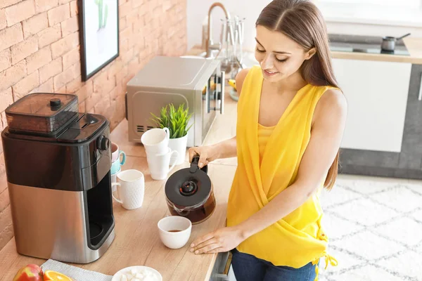 Mulher bonita usando máquina de café na cozinha — Fotografia de Stock