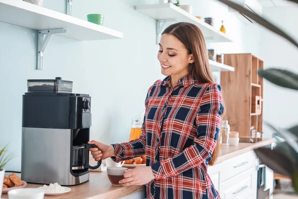 Beautiful woman using coffee machine in kitchen — Stock Photo, Image