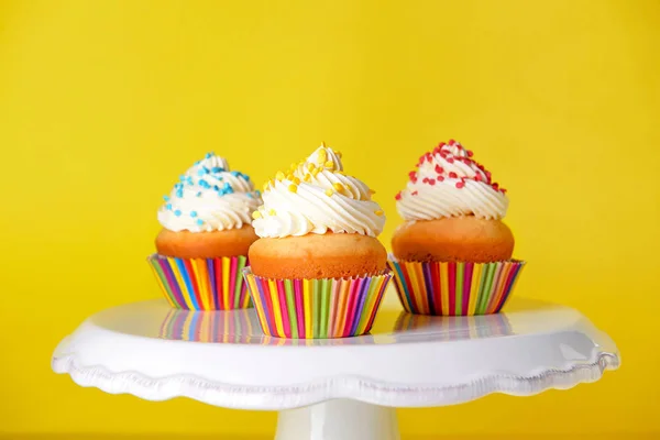 Stå med välsmakande födelsedag cupcakes på färg bakgrund — Stockfoto