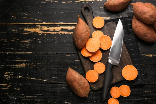 Cutting board and knife with raw sweet potato on wooden background — Stock Photo, Image